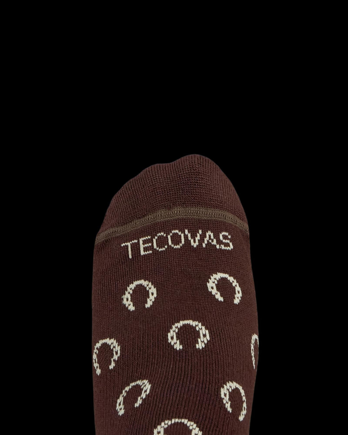 Brown sock with the word "Tecovas" and a pattern of light-colored horseshoes on the top, photographed against a white background.