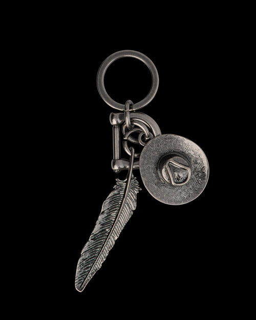 Metal keychain with a feather charm and a cowboy hat charm attached to a round key ring.