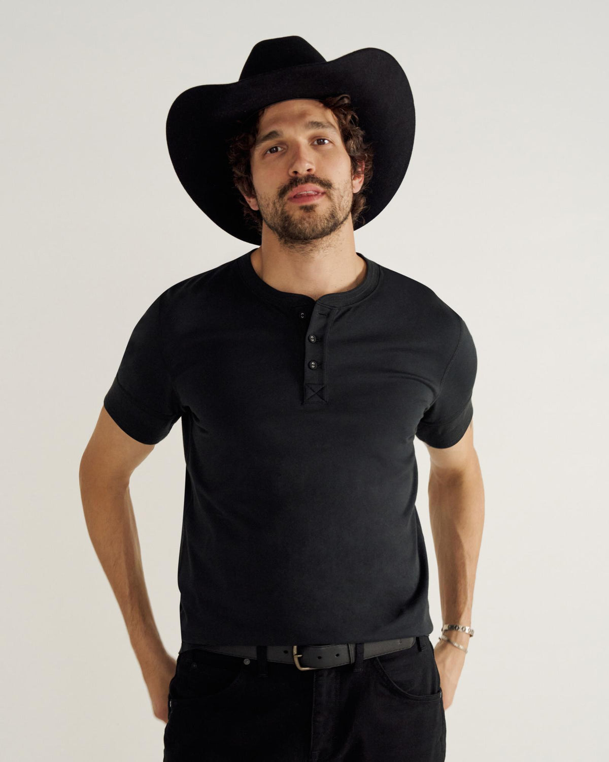 Man wearing a black henley in a studio