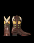 The Jolene in Truffle Cowhide. Brown leather cowboy boots with yellow floral and green leaf appliqués on the shaft, cream leather trim, and a stacked heel—crafted with premium truffle cowhide. Shown from front and side angles.