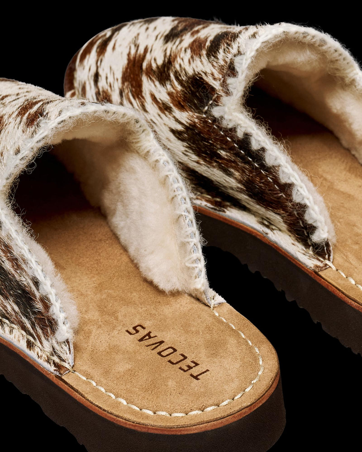 The Olivia in Brown Multi Hair on Hide. Tecovas Olivia hair-on-hide slippers with brown and white cowhide uppers, lined with cream shearling.