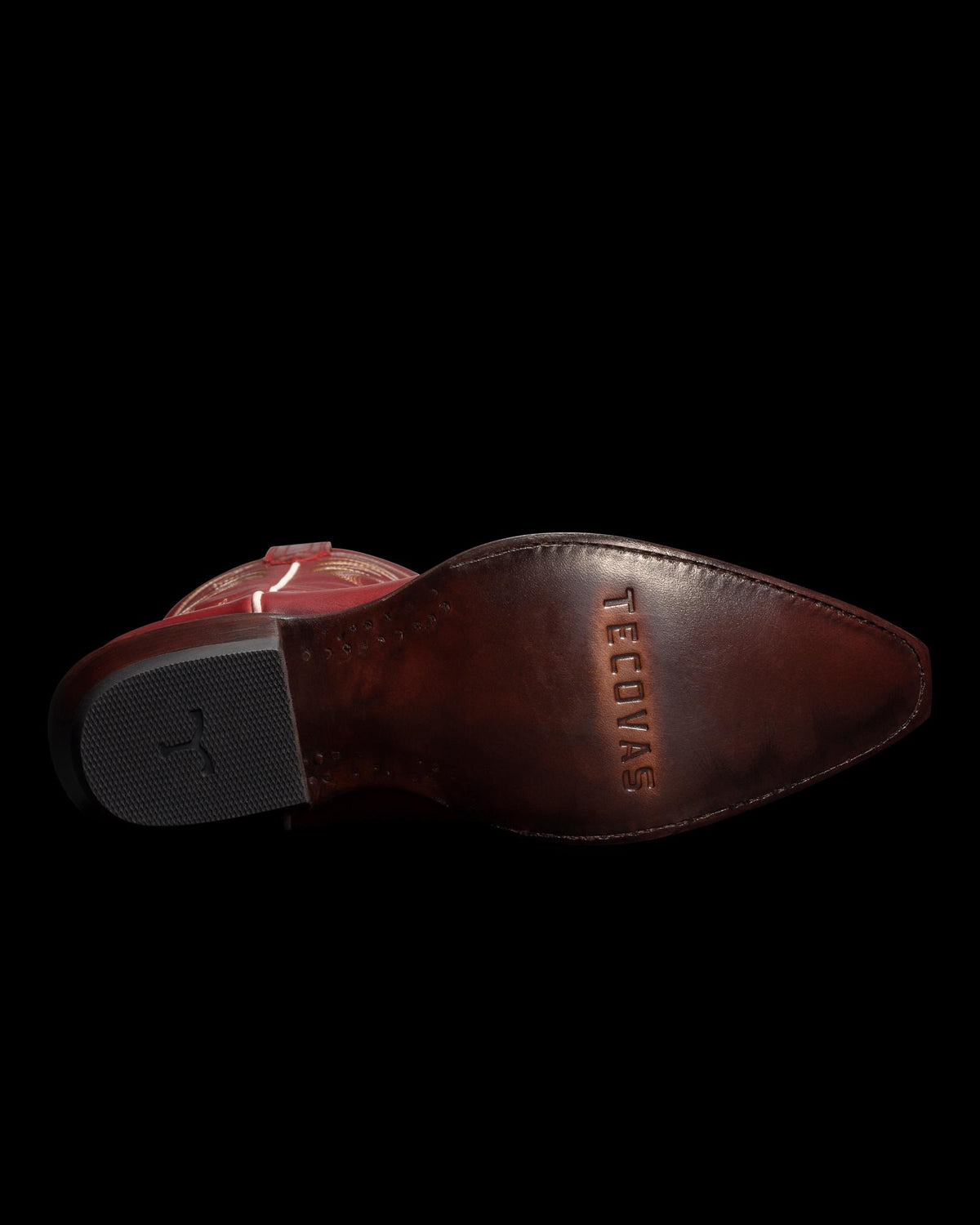Brown leather sole of a boot featuring the word "Tecovas" stamped on it, displayed against a black background.