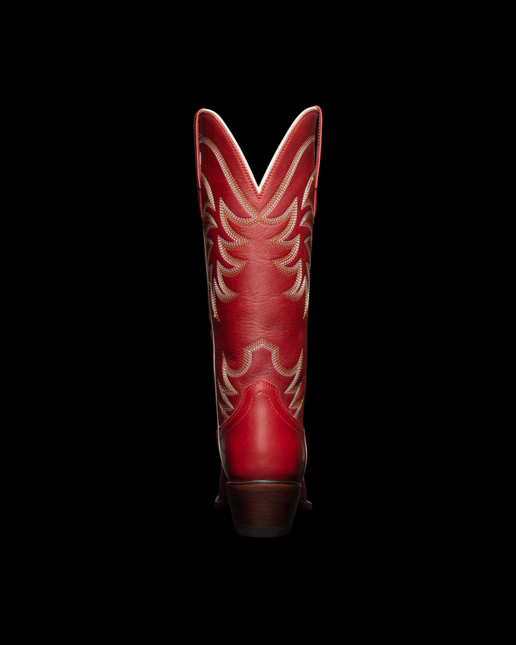 Red cowboy boot with tan decorative stitching, shown from the back against a black background.