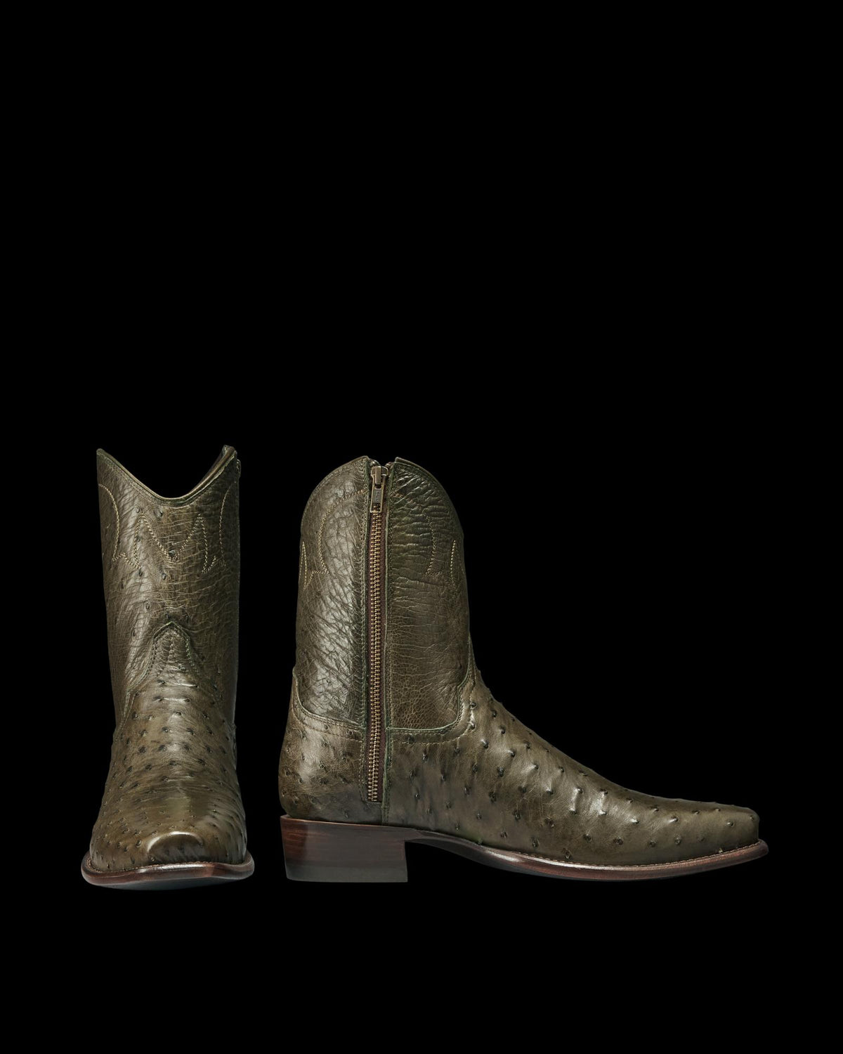 The Jack in Dark Forest Ostrich. A pair of olive green Dark Forest Ostrich leather boots with a side zipper, pointed toes, and low wooden heels, displayed on a white background.