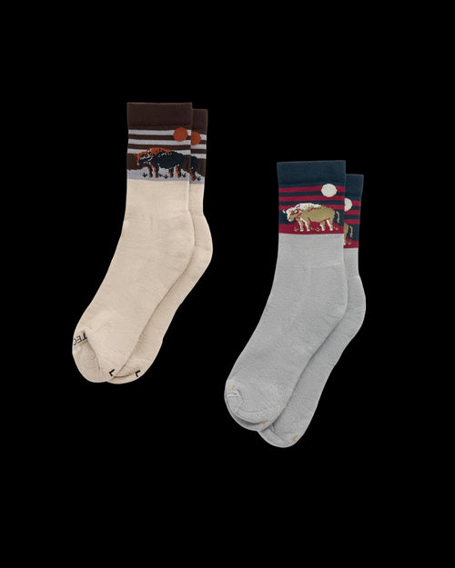 Two pairs of socks: one beige with a bear design and one light blue with a bison design, both featuring nature-themed patterns near the cuffs.