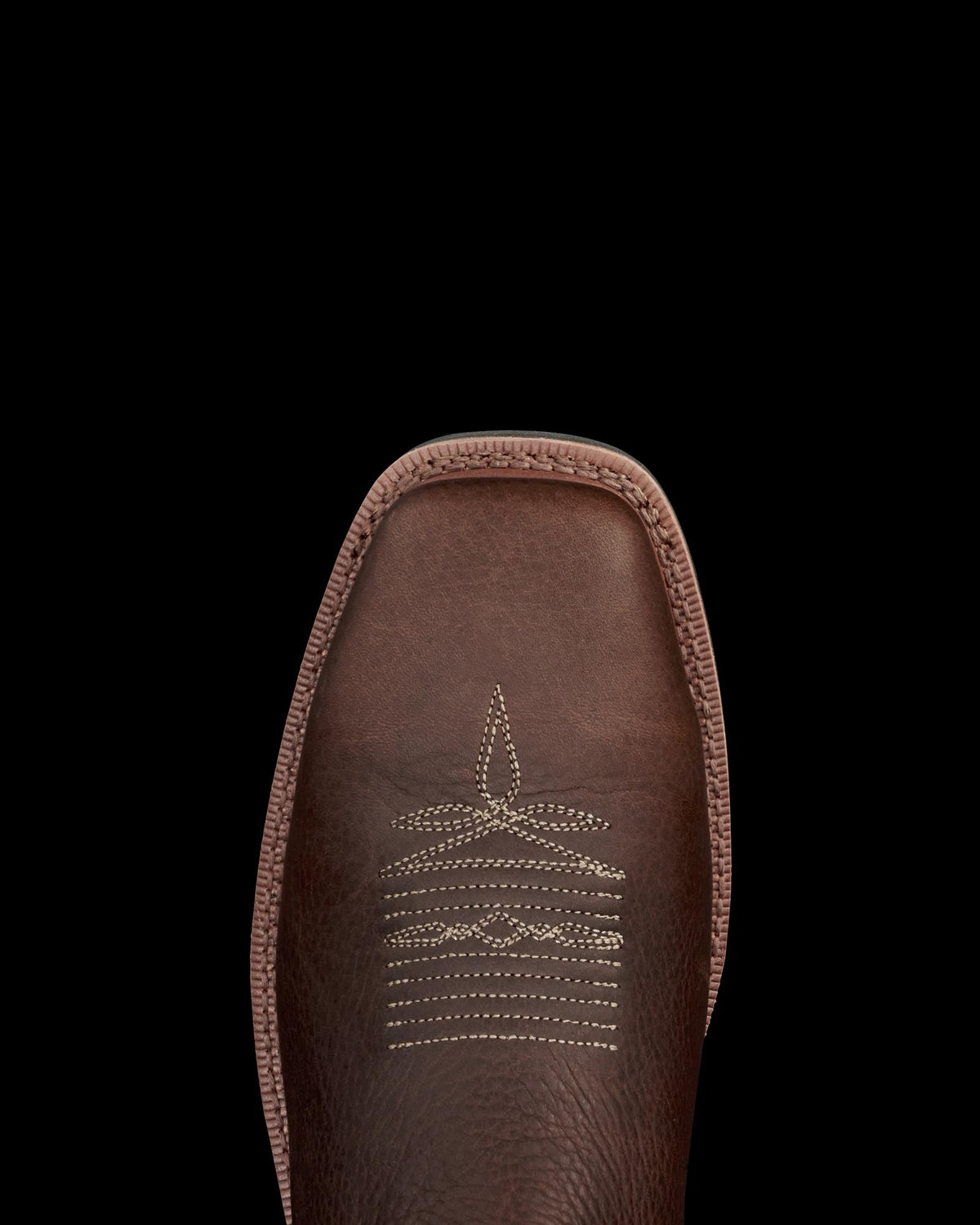 LongHaul Waterproof Square Composite Toe Work Boot in Tobacco / Black Cowhide. A close-up of the toe of a Tobacco / Black cowhide leather boot with white decorative stitching, set against a black background.