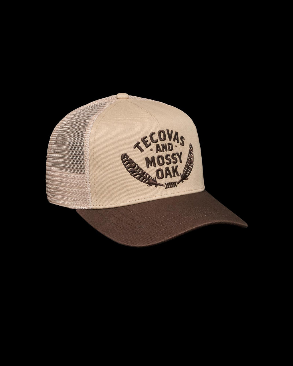 A beige and brown trucker hat with mesh back, featuring "Tecovas and Mossy Oak" text and two feather graphics on the front.