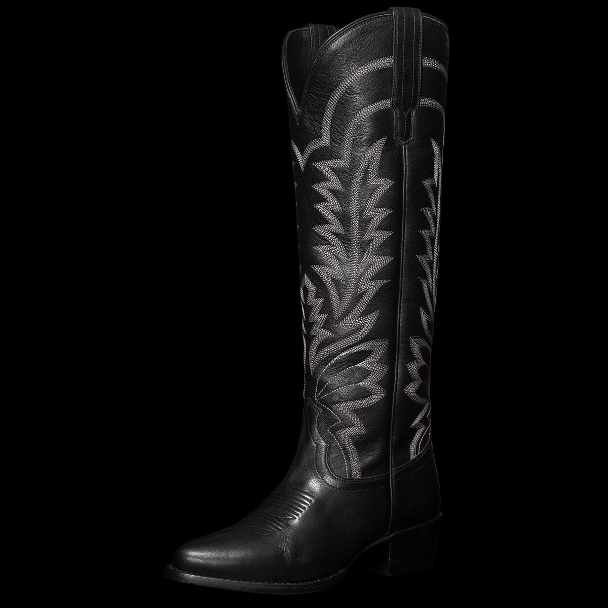 Black cowboy boot with intricate white stitching and a pointed toe.