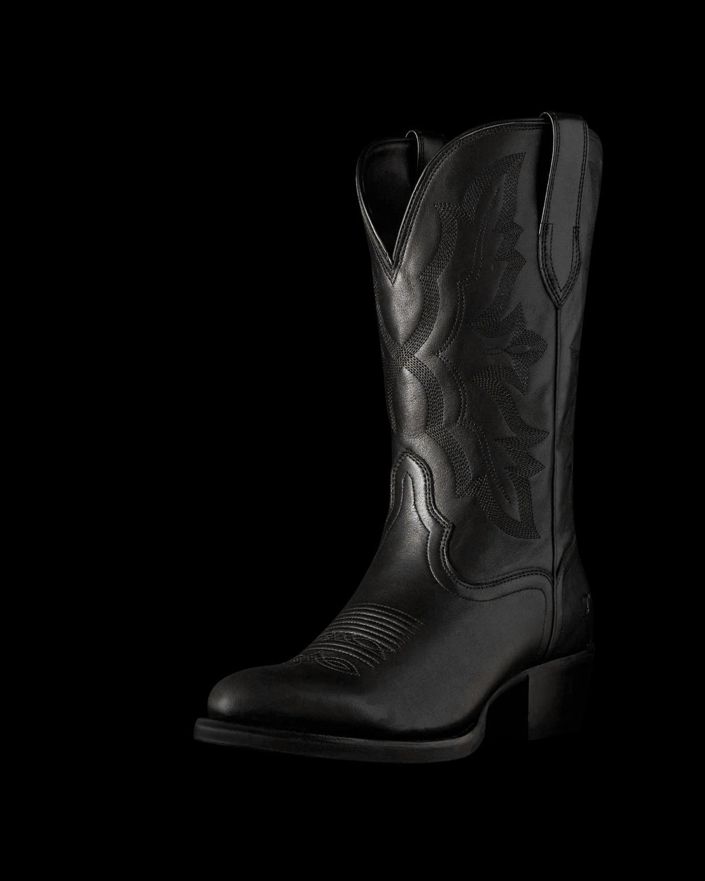 The Britt in Midnight Cowhide. Black leather cowboy boot crafted from Midnight Cowhide, featuring decorative stitching, a pointed toe, mid-calf height, pull tabs, and a low angled heel, displayed on a plain white background.