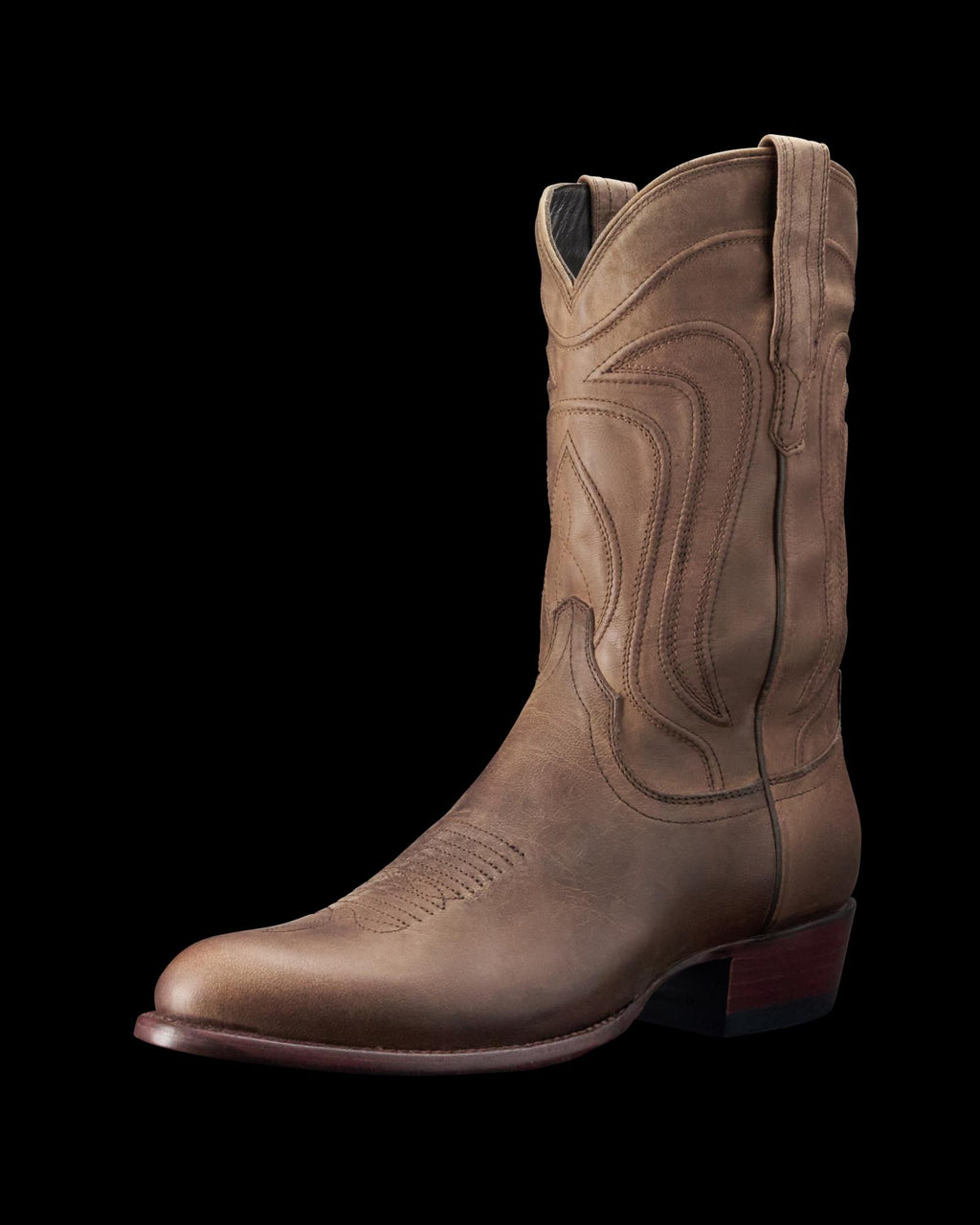 A single brown cowboy boot with decorative stitching, a pointed toe, and a low heel, displayed against a black background.