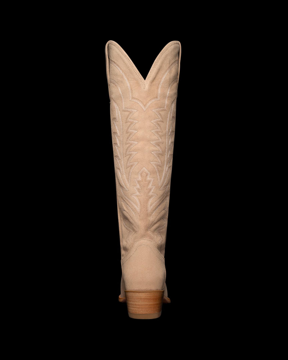 Back view of a beige cowboy boot with decorative stitching on the shaft, against a black background.