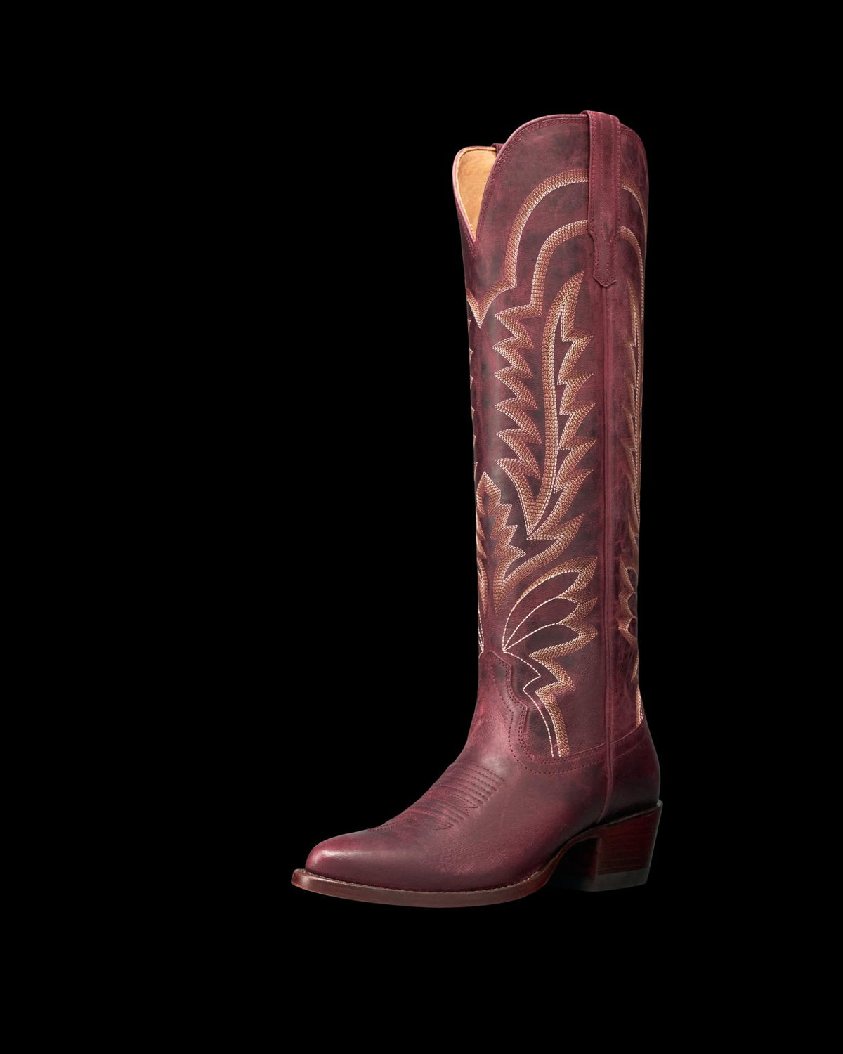 The Abby in Wine Goat. A single tall, maroon cowboy boot with decorative stitching, a pointed toe, and a low angled heel stands against a plain white background—evoking the rich hue of Wine Goat.