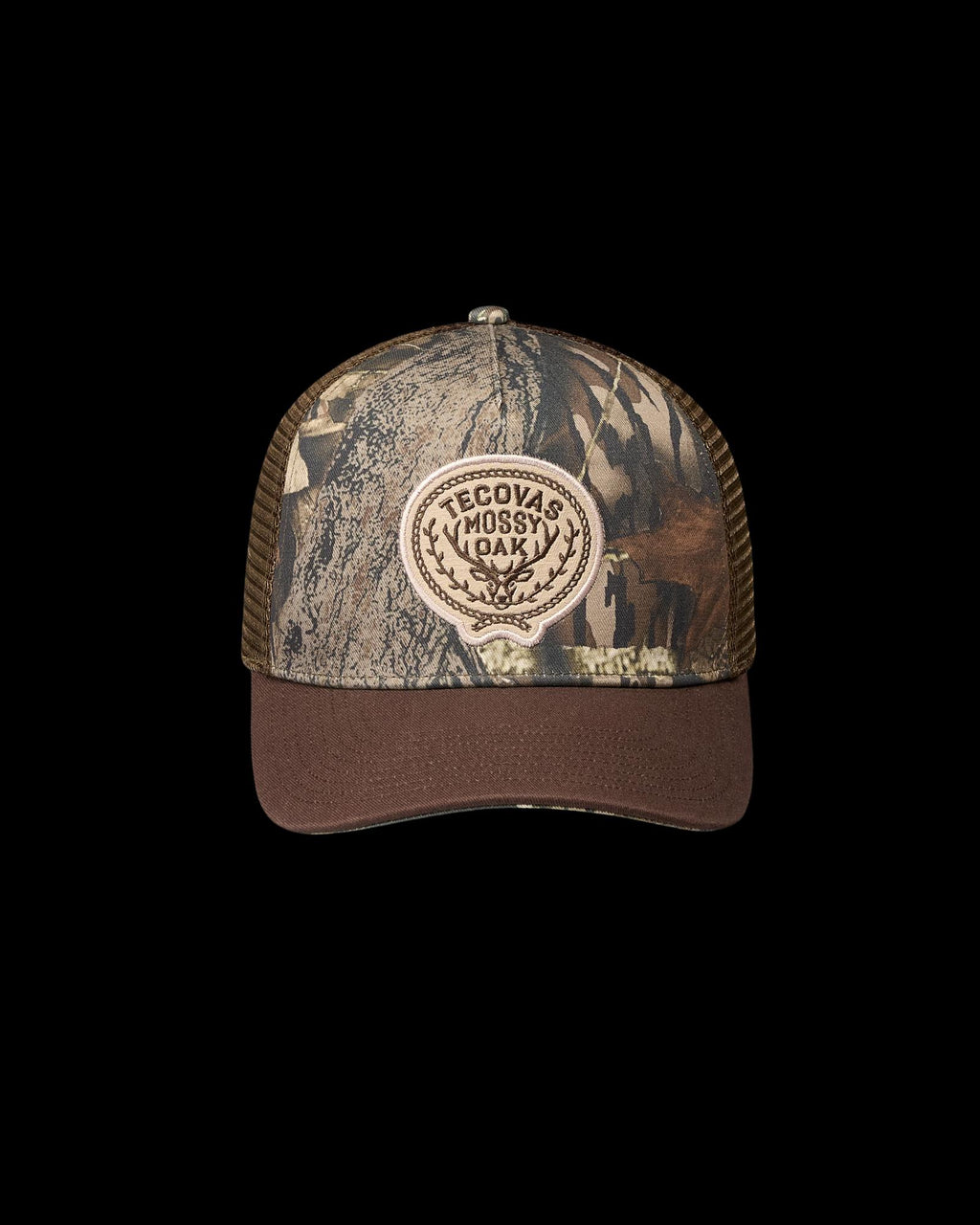 A camouflage-patterned trucker hat with a mesh back and a front patch that reads “Tecovas Mossy Oak.”.