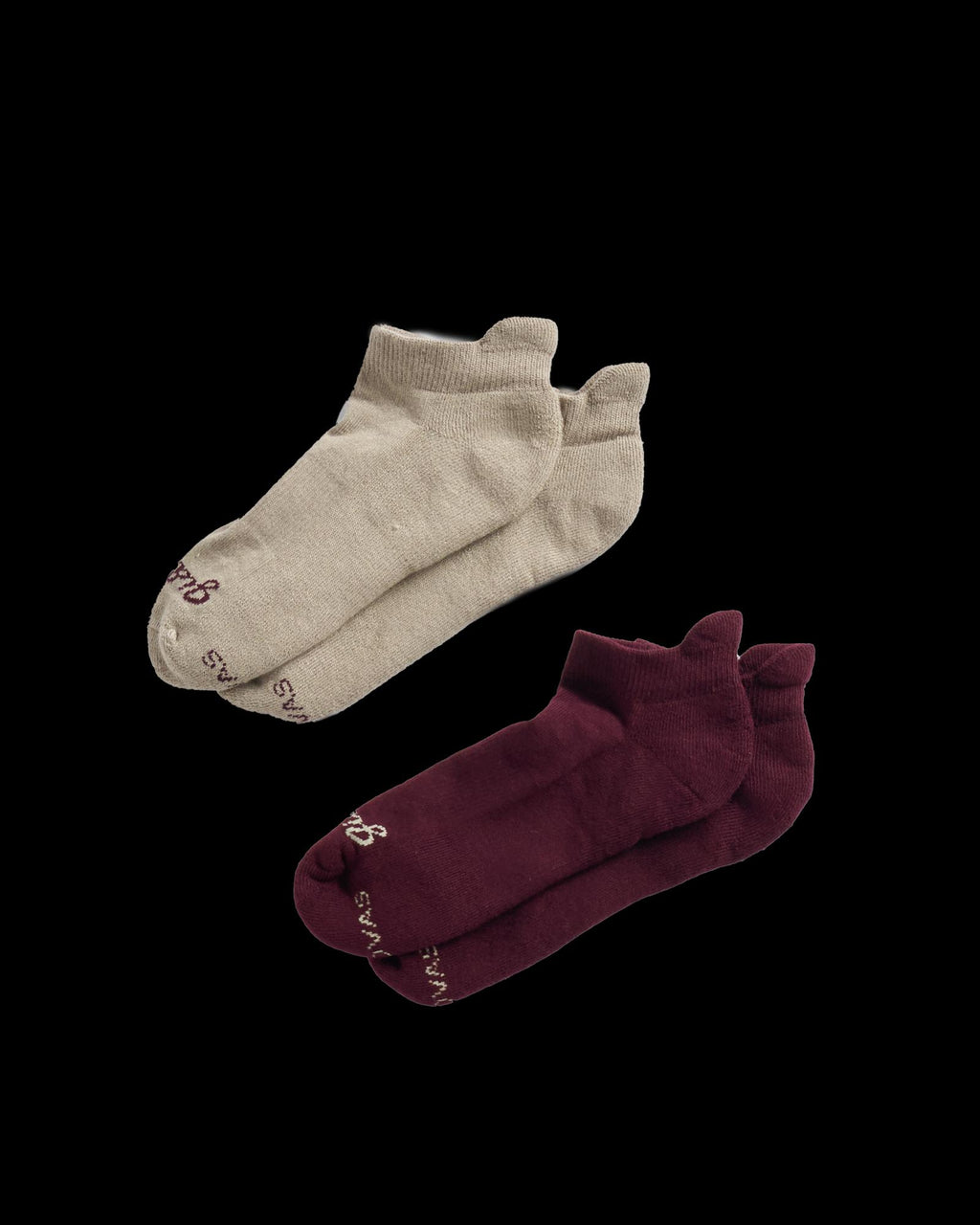 Two pairs of ankle socks, one beige and one dark red, are displayed on a black background.