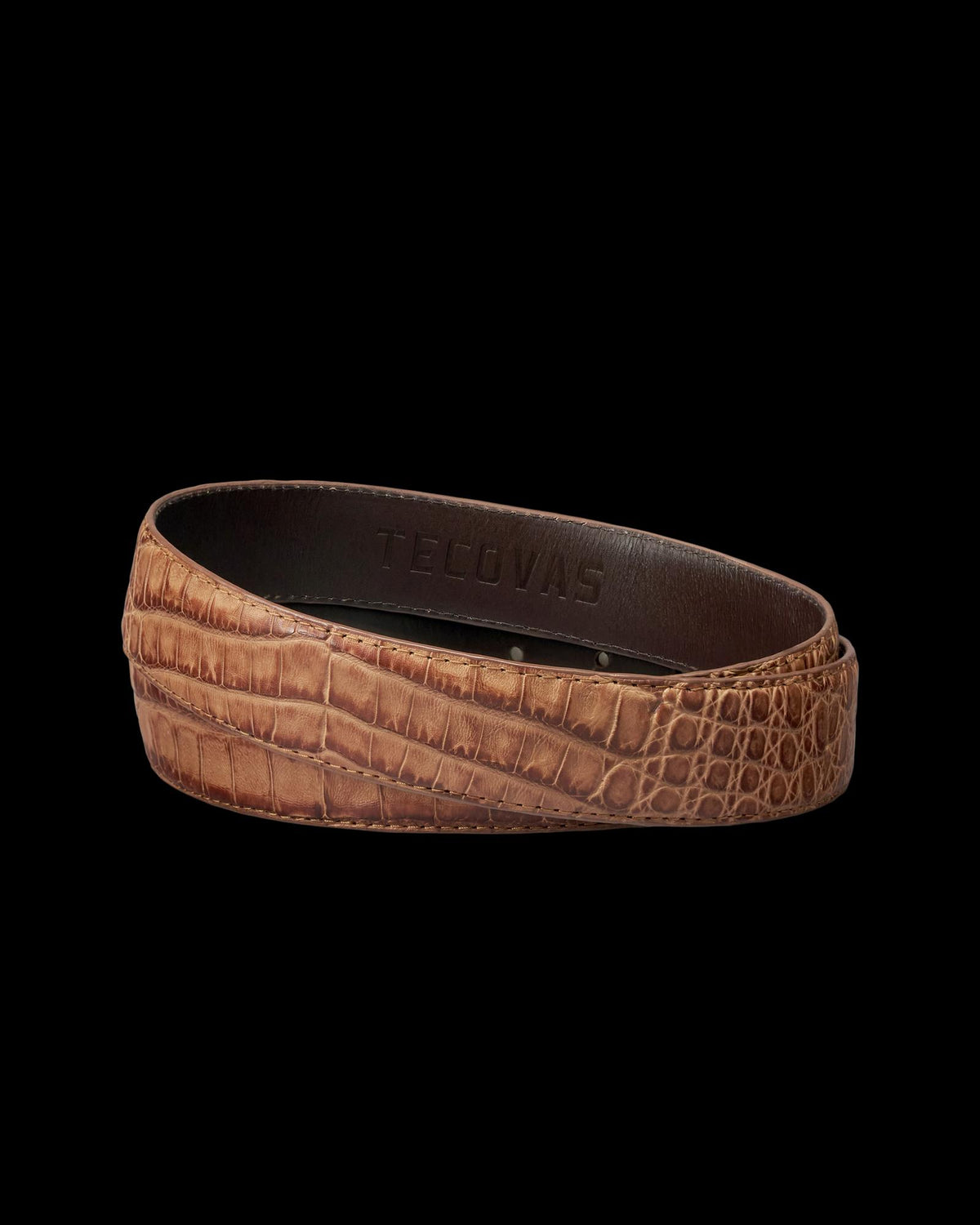 A brown crocodile-embossed leather belt with "Tecovas" stamped on the inner side, displayed coiled on a white background.