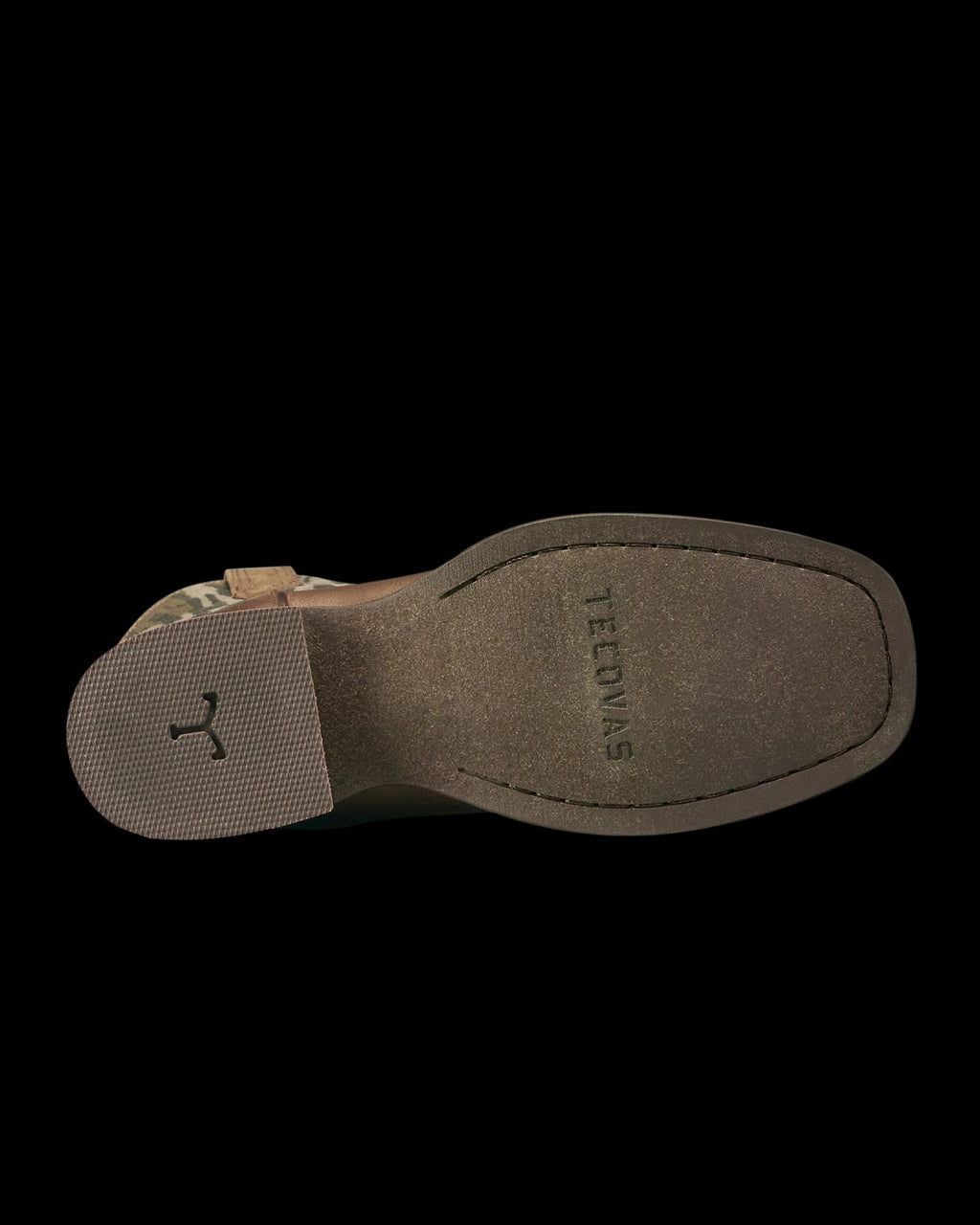 Bottom view of a brown shoe with a textured heel and a grooved marking, “TEJONAS,” stamped on the sole.
