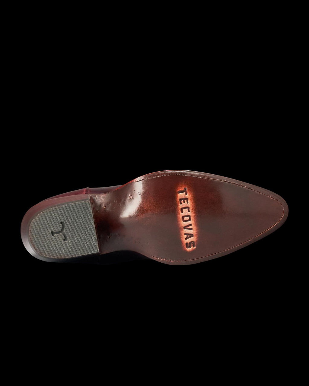 The Abby in Wine Goat. The polished leather sole of a Wine Goat shoe is shown from below, with the word "Tecovas" engraved and a textured gray heel patch visible.