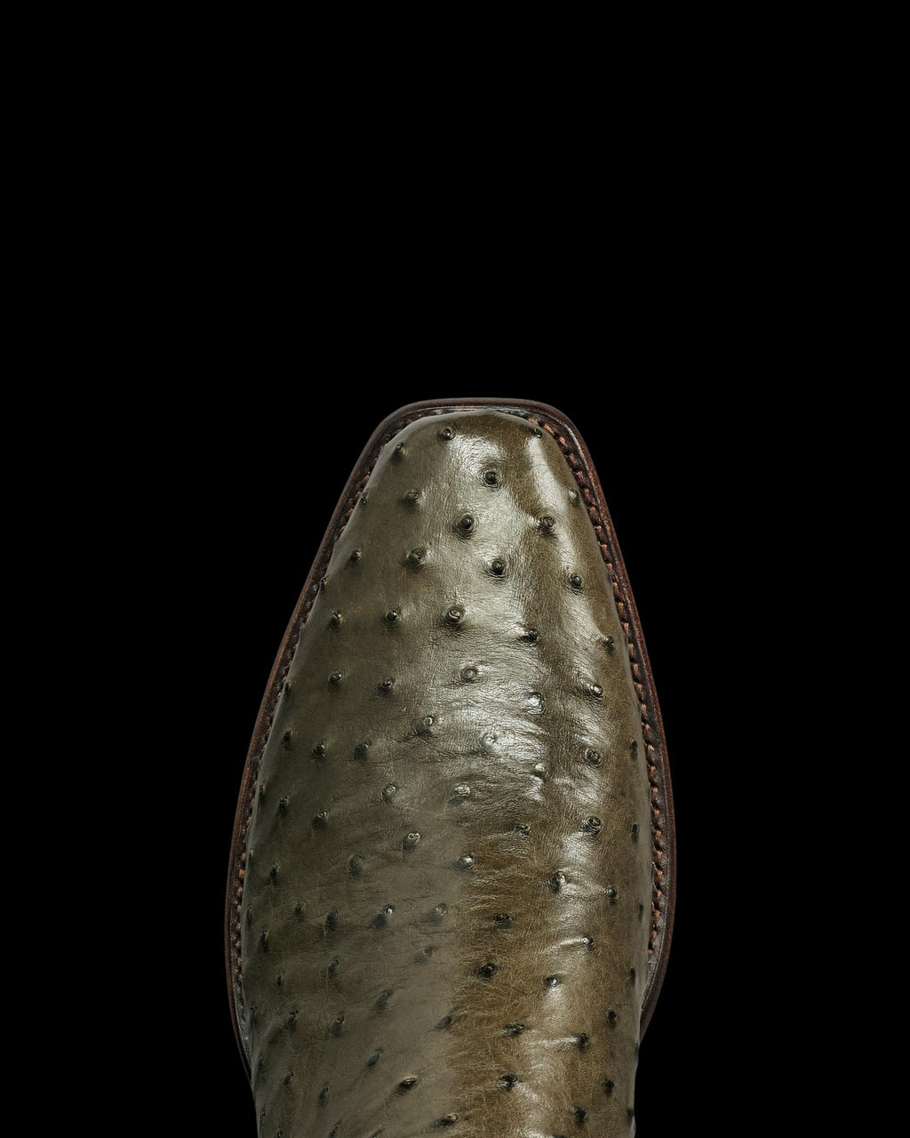 Close-up of the toe of The Jack Ostrich cowboy boot in a distinctive Dark Forest greenish-brown ostrich leather, featuring visible quill bumps and precise stitching along the edge.