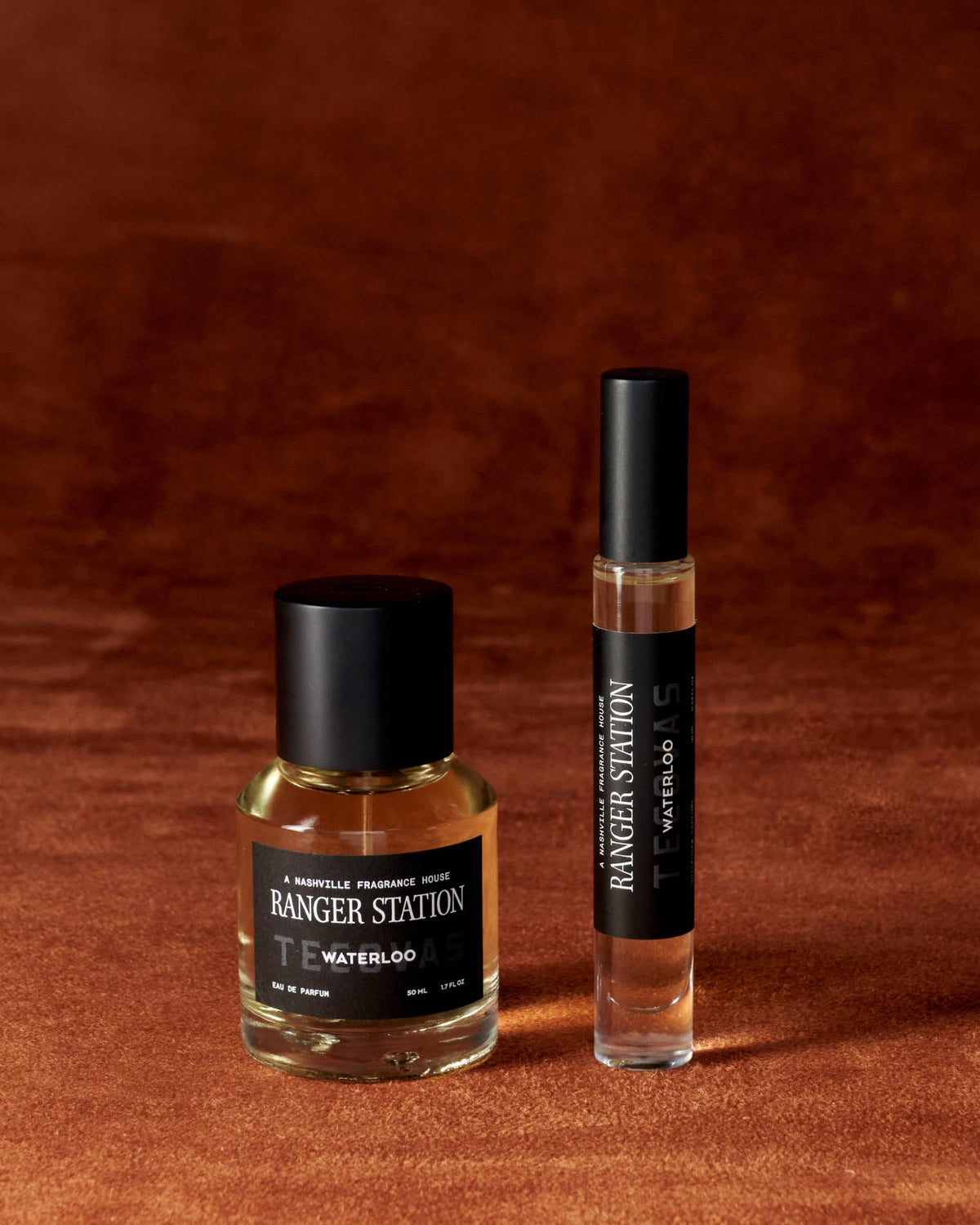 A bottle and a rollerball of Ranger Station Waterloo Eau de Parfum are placed on a brown textured surface.