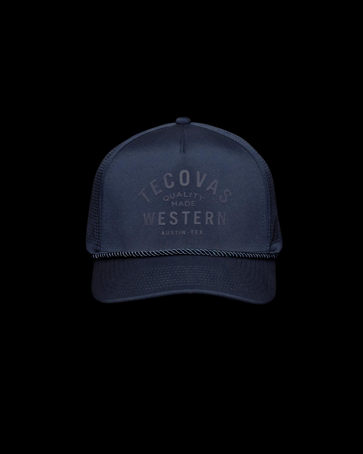 Navy blue trucker hat with mesh back, black rope detail above the brim, and "Tecovas Quality Made Western Austin, Tex." printed on the front.