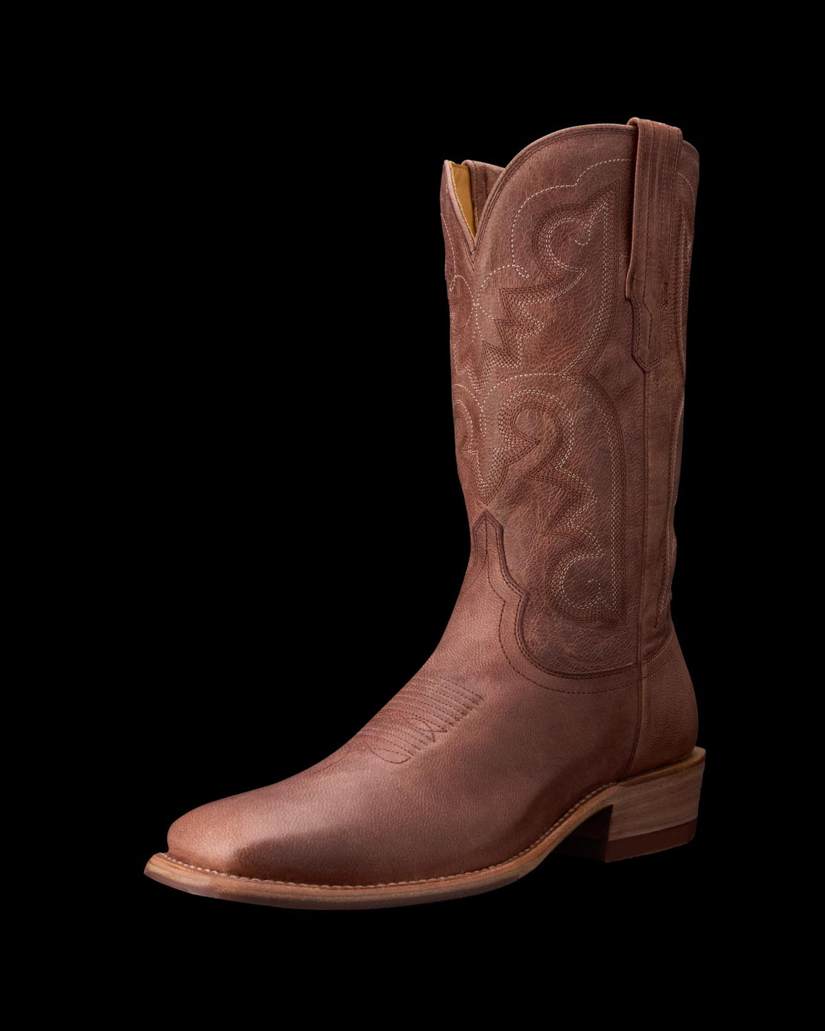 Brown cowboy boot with intricate stitching and a stacked heel, displayed on a black background.