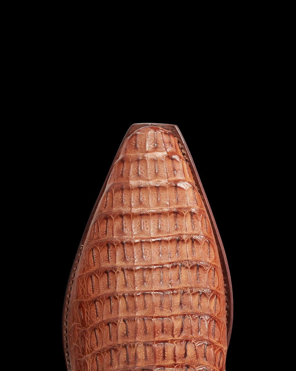 Close-up of the pointed toe of The Garrett Hornback Caiman shoe in pecan, featuring an embossed crocodile skin pattern, viewed from above against a white background.
