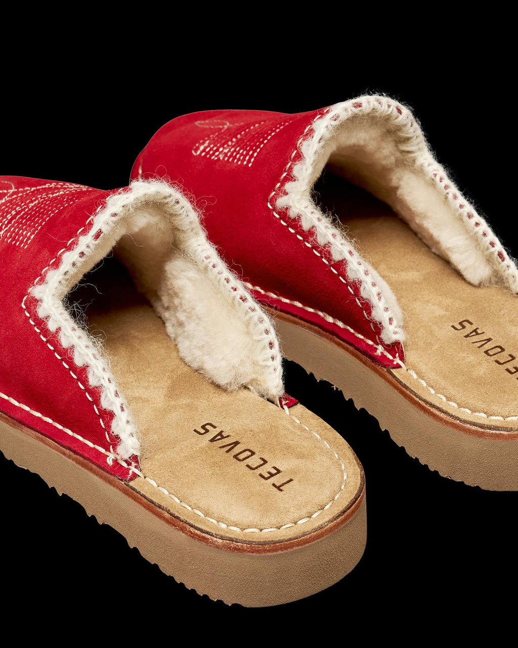 The Olivia Suede slip-on mules in cherry feature a red suede upper, white shearling lining, and tan footbeds stamped with the Tecovas logo.