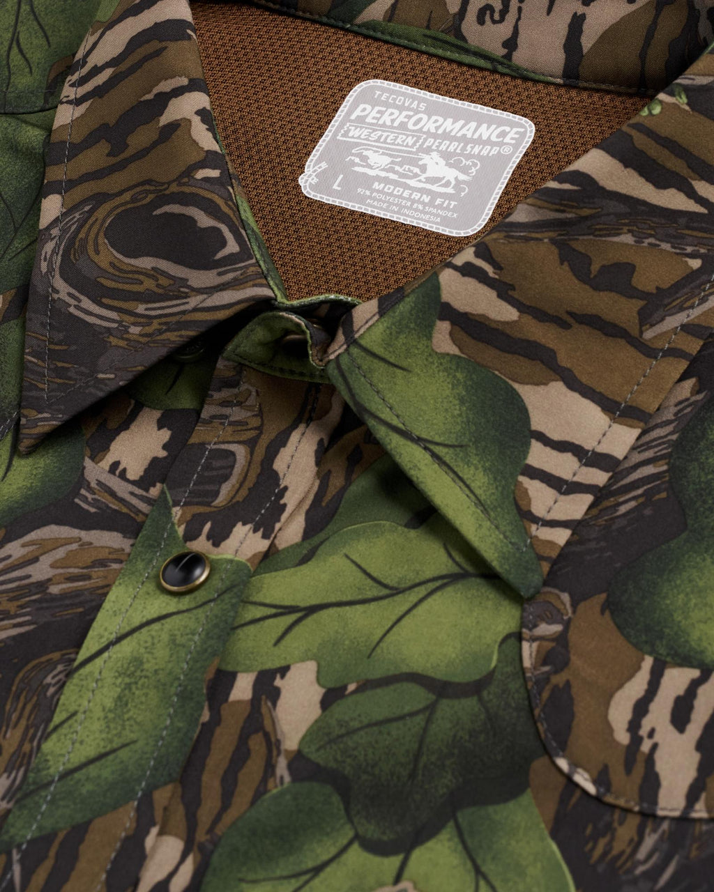 Close-up of a button-down shirt with a green and brown camouflage pattern and a visible label reading "Performance Western Shirt, Modern Fit, L.