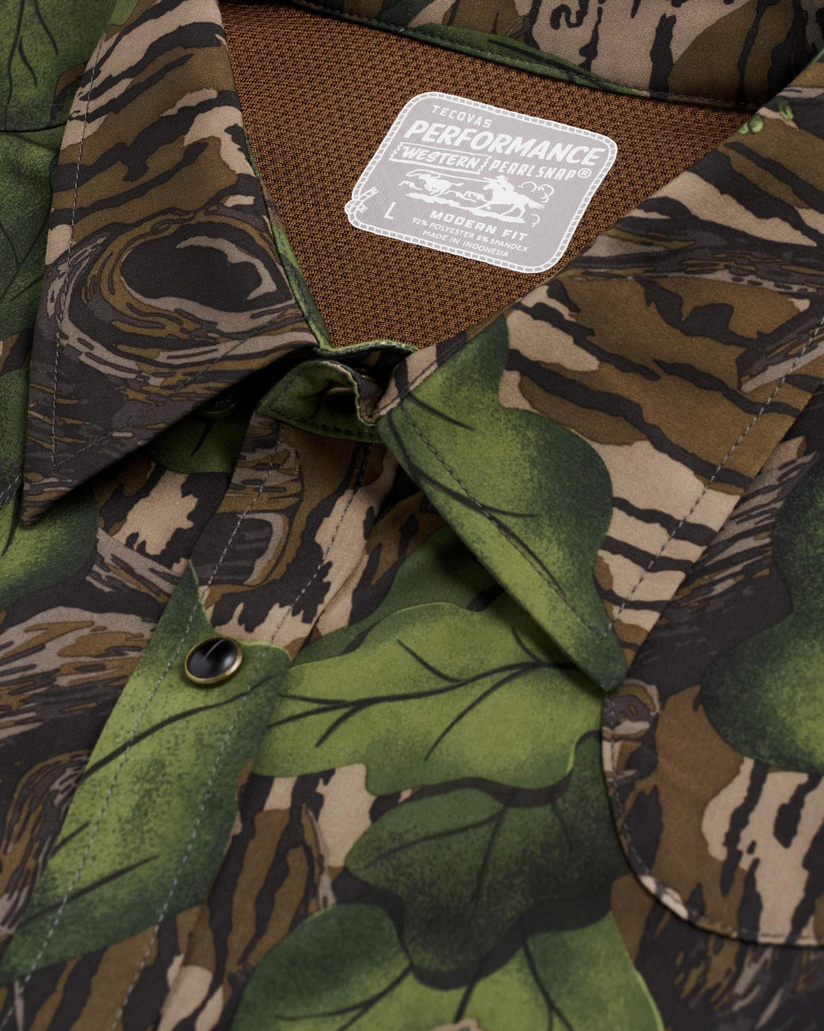Close-up of a button-down shirt with a green and brown camouflage pattern and a visible label reading "Performance Western Shirt, Modern Fit, L.