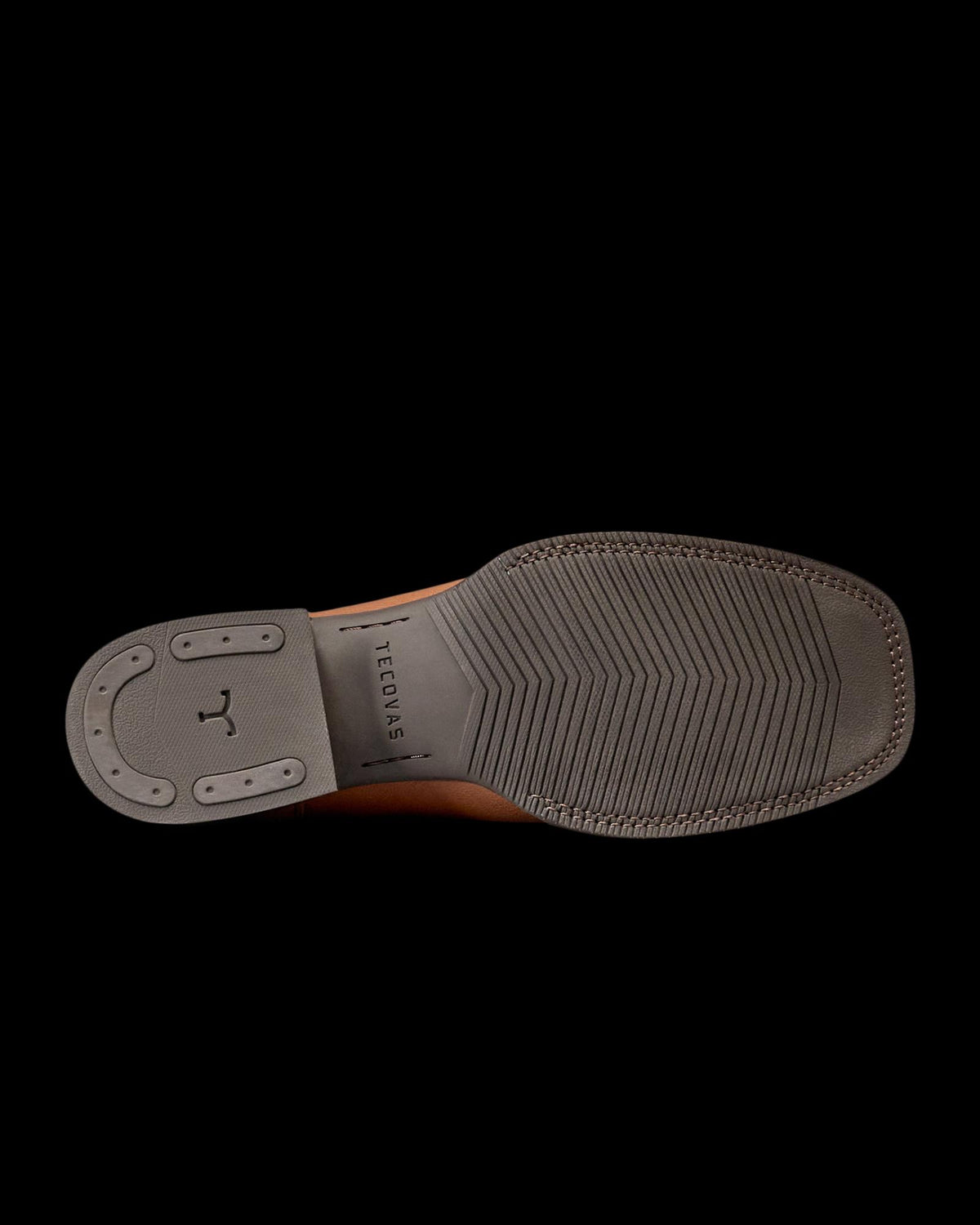 The Dusty in Mesa Goat. The image shows the bottom view of a brown dress shoe from The Dusty Goat, with a gray rubber sole featuring textured grip and the word “TECTONIC” engraved near the arch.