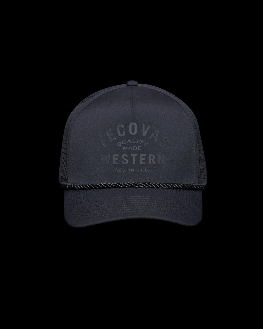 A black baseball cap with the text "Tecovas Quality Made Western Austin, Tex." on the front. It features a mesh back and a rope across the brim.