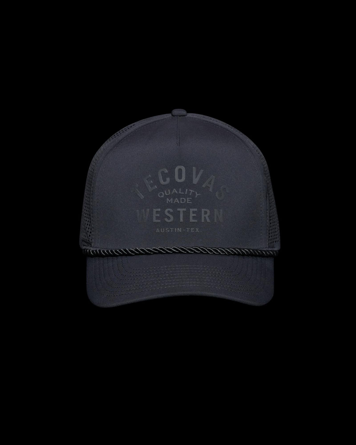 A black baseball cap with the text "Tecovas Quality Made Western Austin, Tex." on the front. It features a mesh back and a rope across the brim.