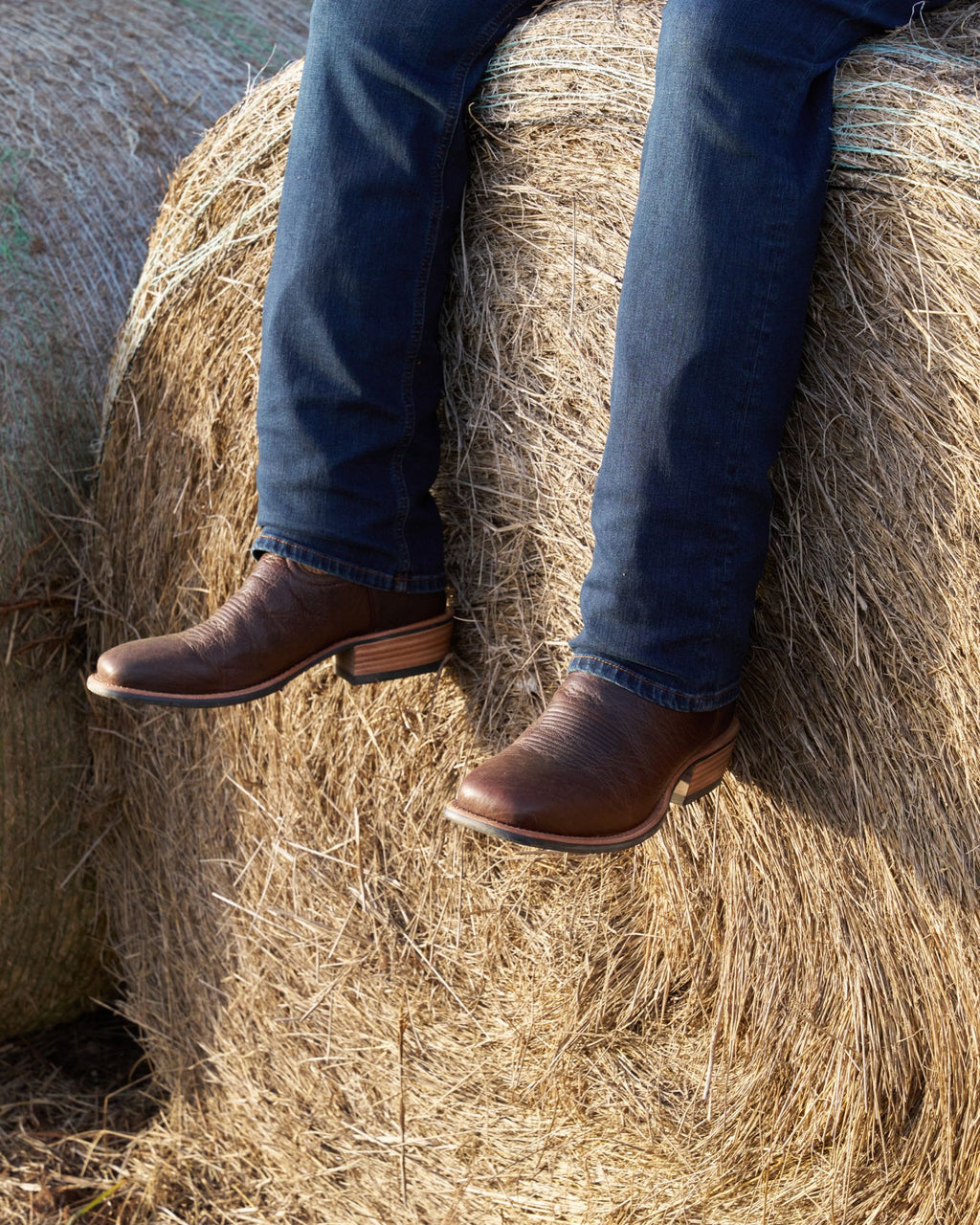 Man wearing the cody chocolate sitting on a barrel of hay