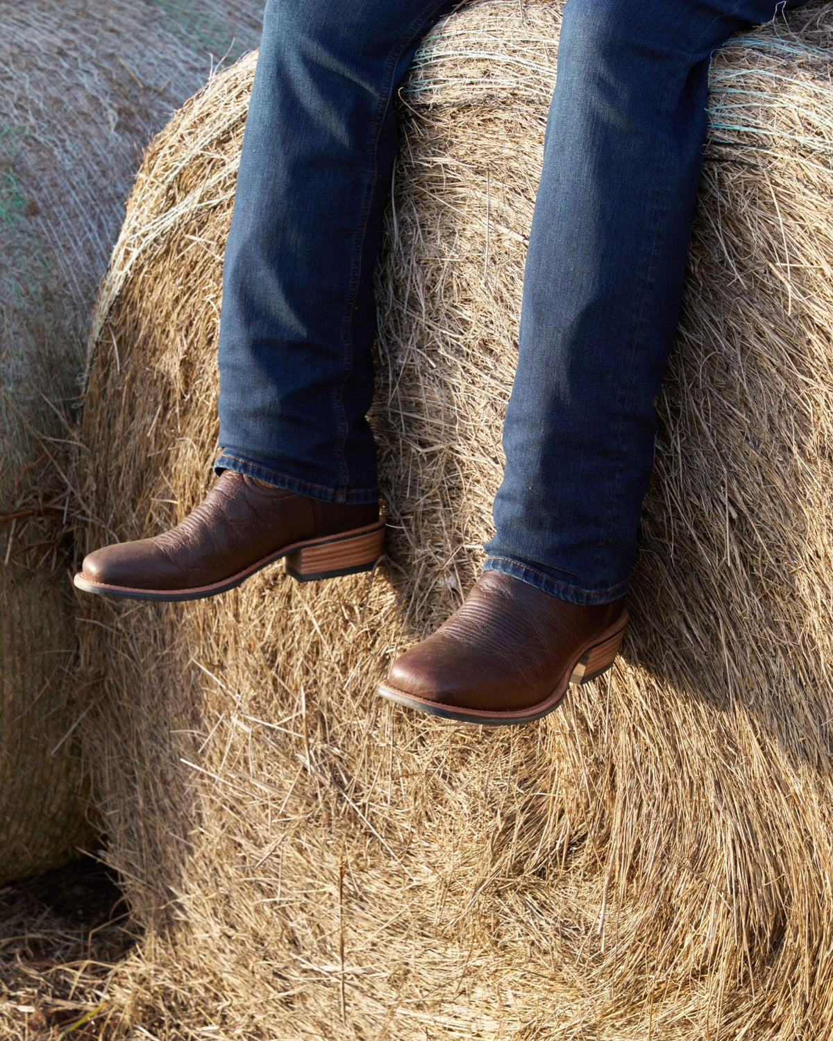 Man wearing the cody chocolate sitting on a barrel of hay