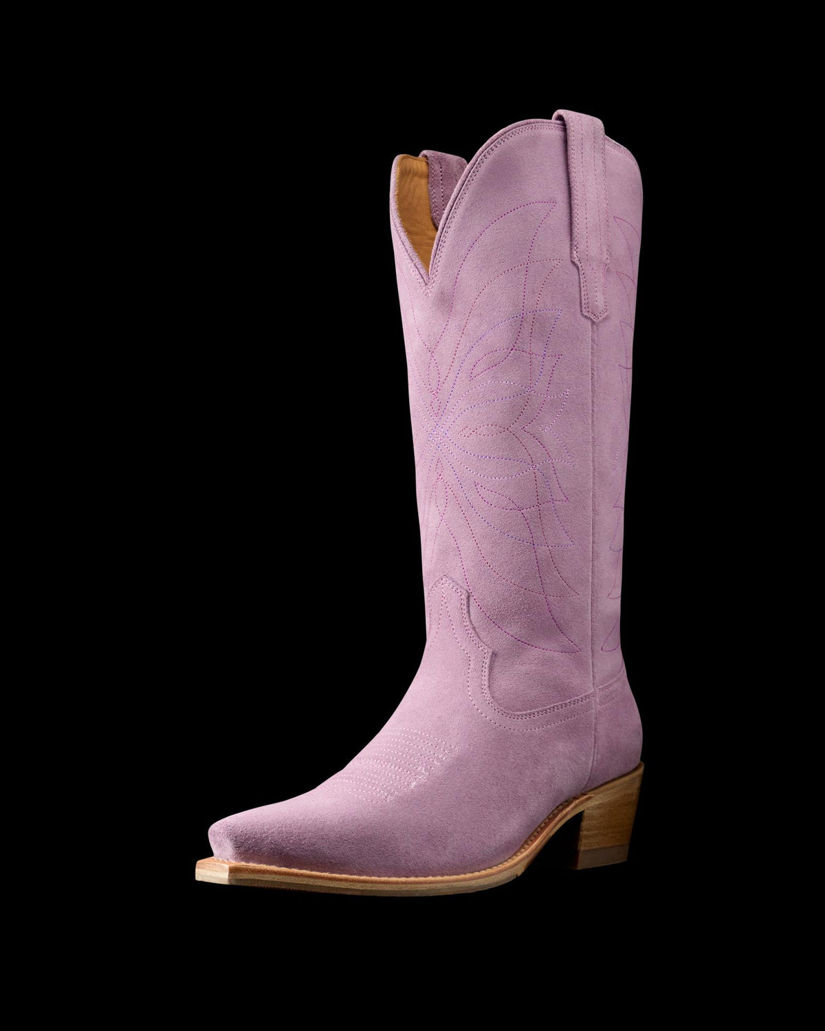 The Annie in Lavender Suede. A single pink Annie Suede cowboy boot with decorative stitching, a pointed toe, wooden heel, and pull tabs on either side.