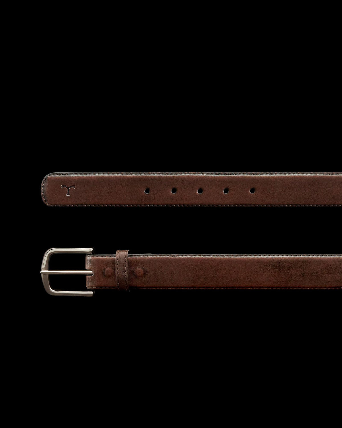 A brown leather belt with a silver buckle, featuring five holes and a small bull logo embossed near the tip.